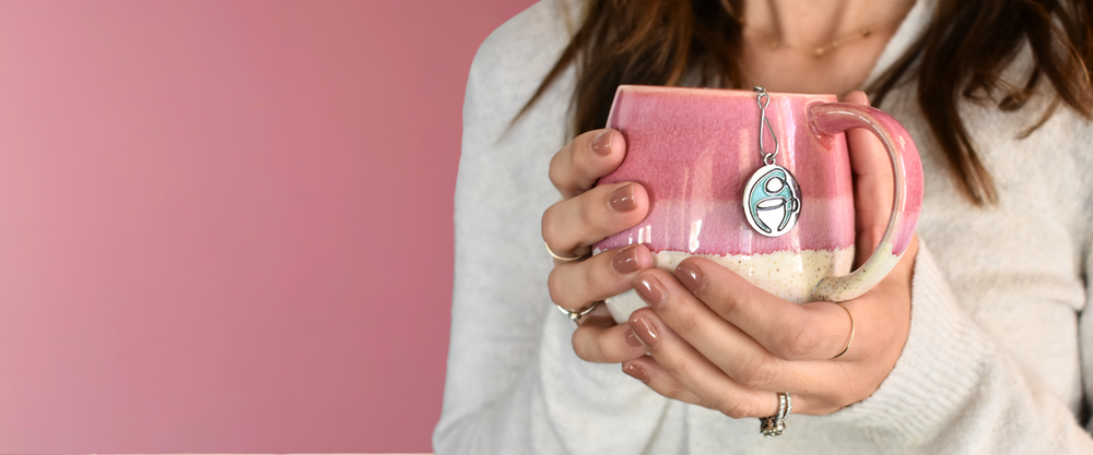 Hands holding a pink mug of tea