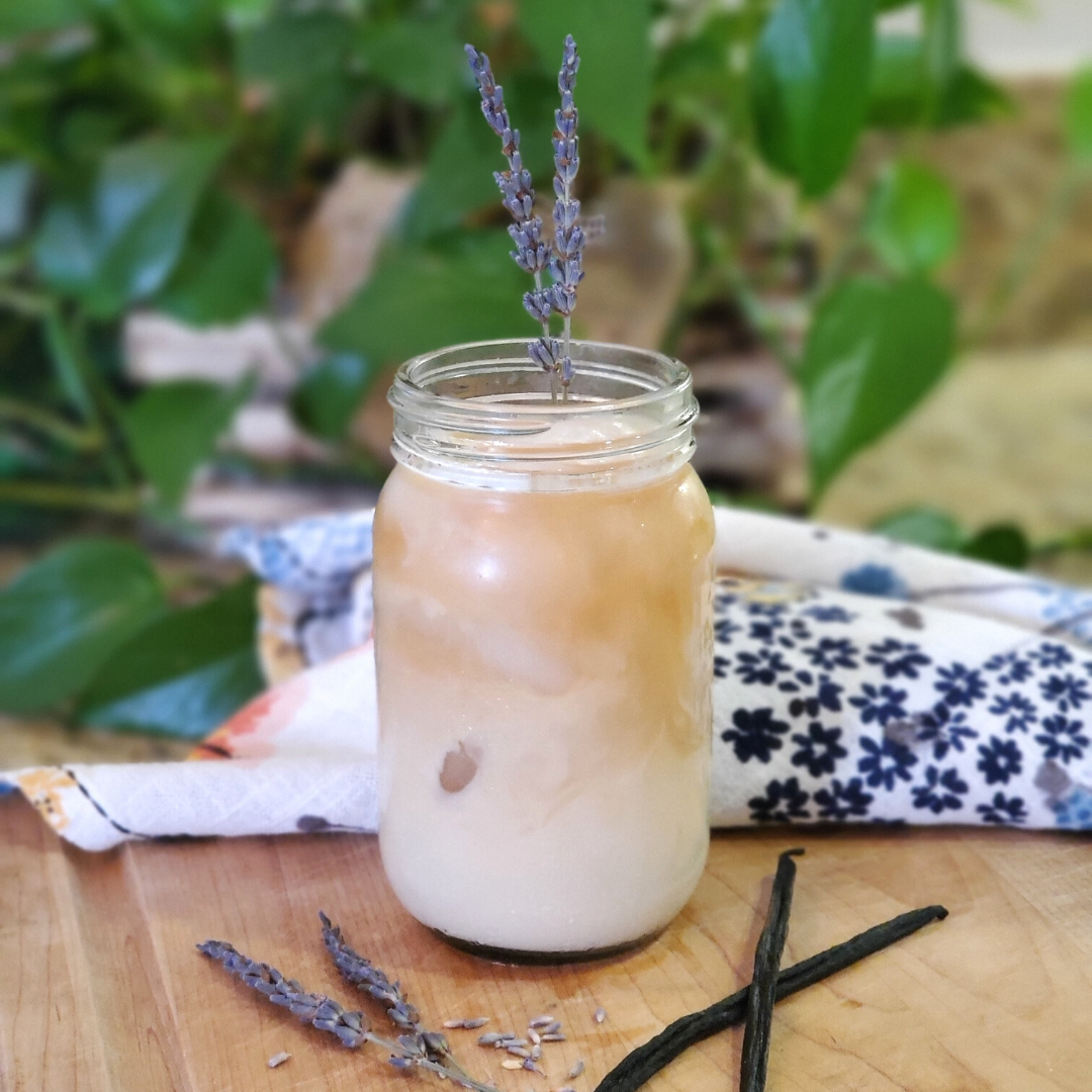 A tall glass of iced Achieve Clarity vanilla Earl Grey latte with lavender and vanilla